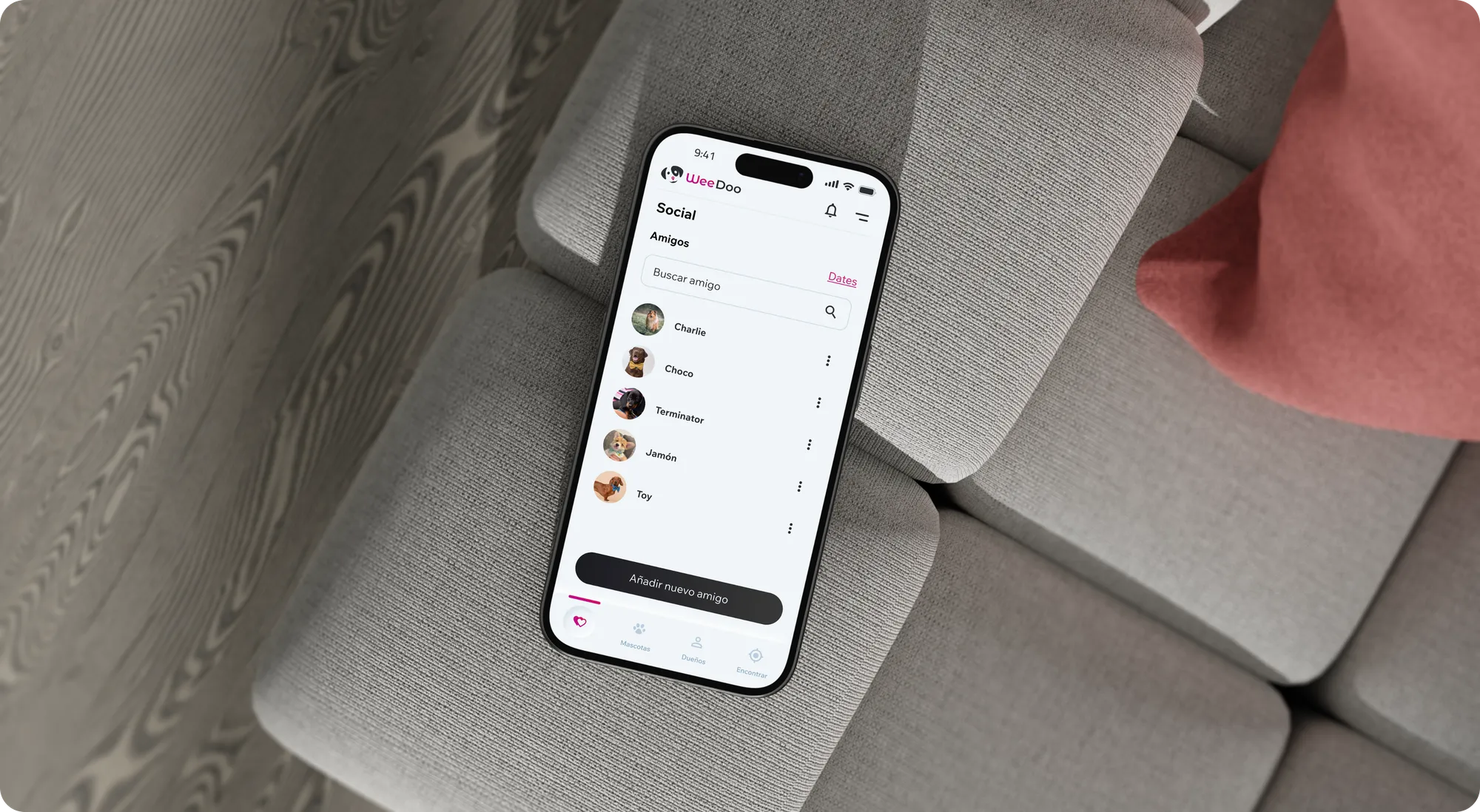 iPhone resting on a grey sofa showing a WeeDoo list of owners and pet data